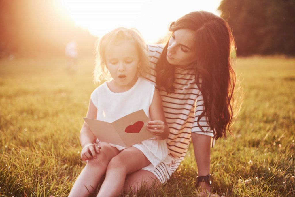 A young mother reading a postcard with her child.
