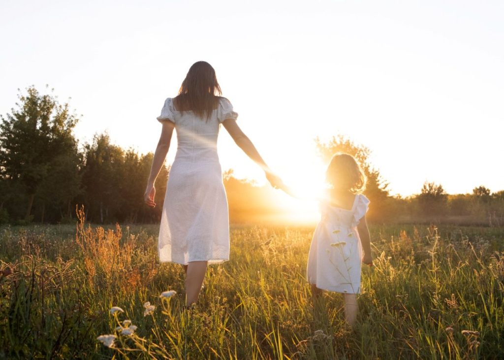A mother and a child walking through the sun.