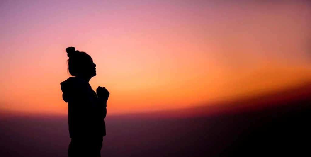 A woman praying during the dawn.