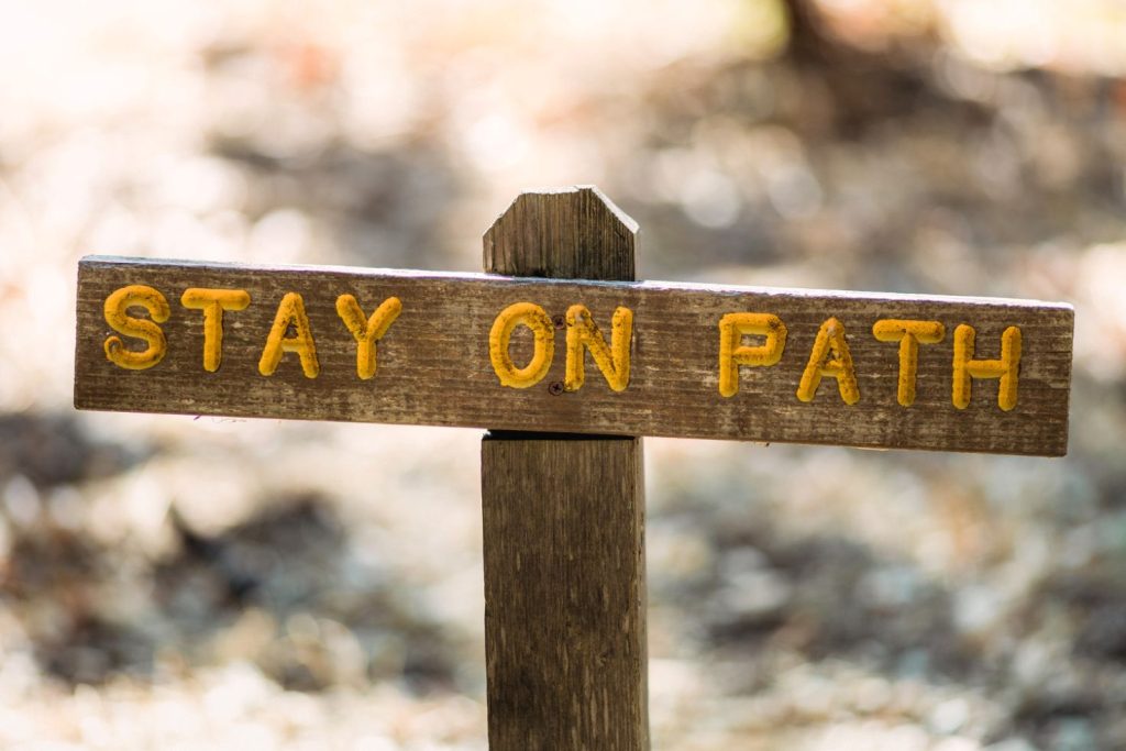 A wooden sign that says “STAY ON PATH.”