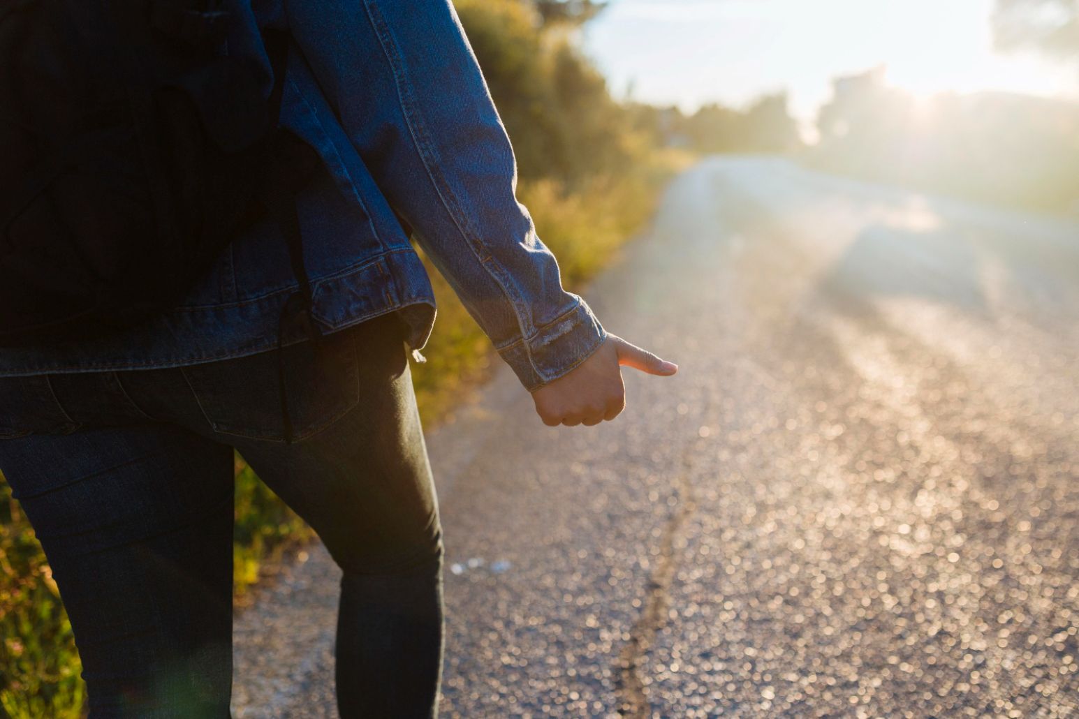 A person walking down the road, waiting for a sign.