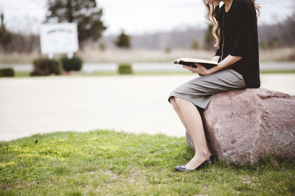    A woman sitting down and reading the Bible.
