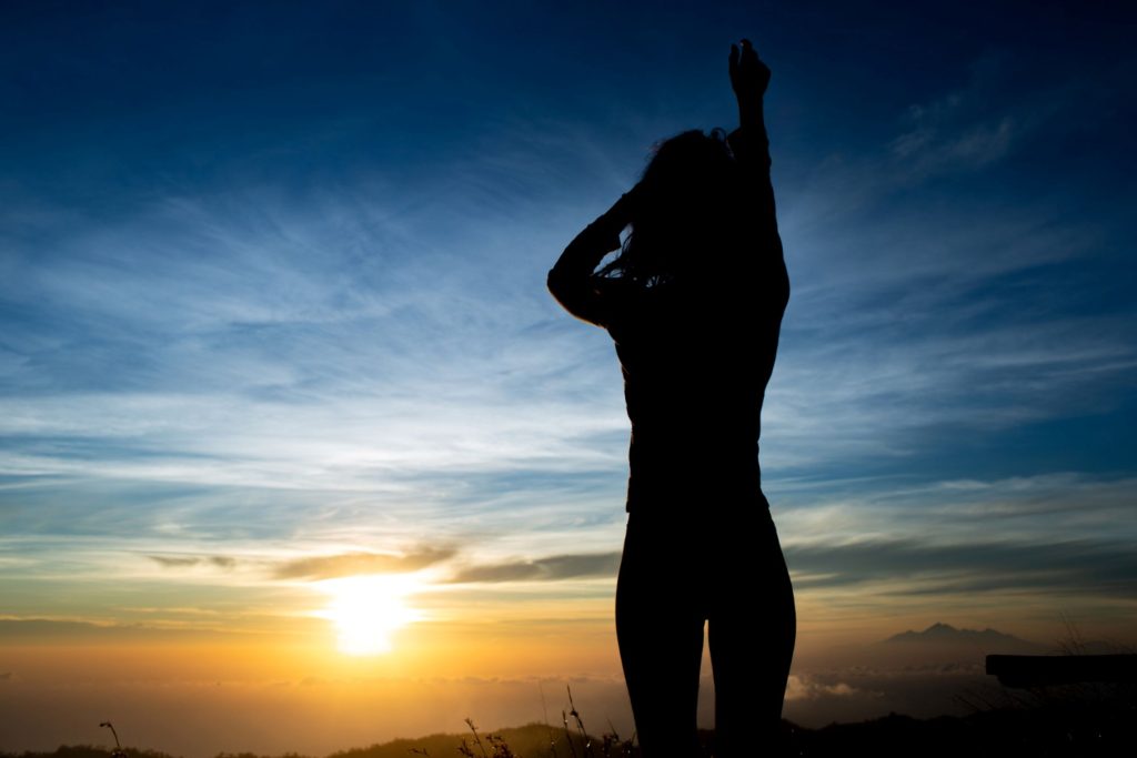 A woman basking in the light from a sunrise.