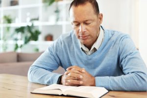 man praying over open Bible for scriptures for healing the heart, seeking peace and emotional healing through faith