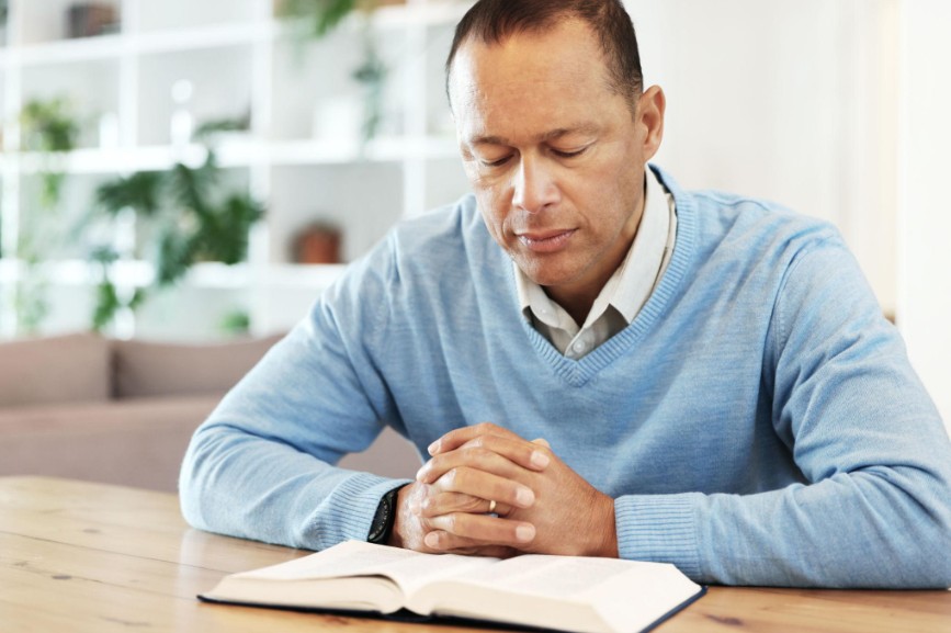 man praying over open Bible for scriptures for healing the heart, seeking peace and emotional healing through faith